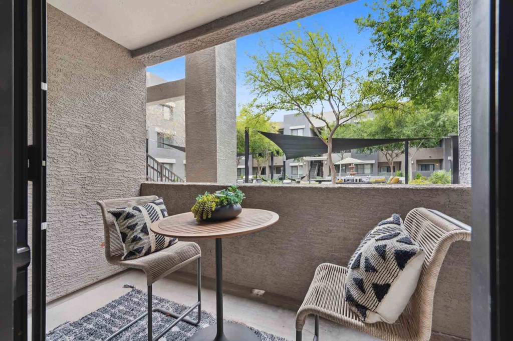 A patio with a table and two chairs with a view of apartment buildings.