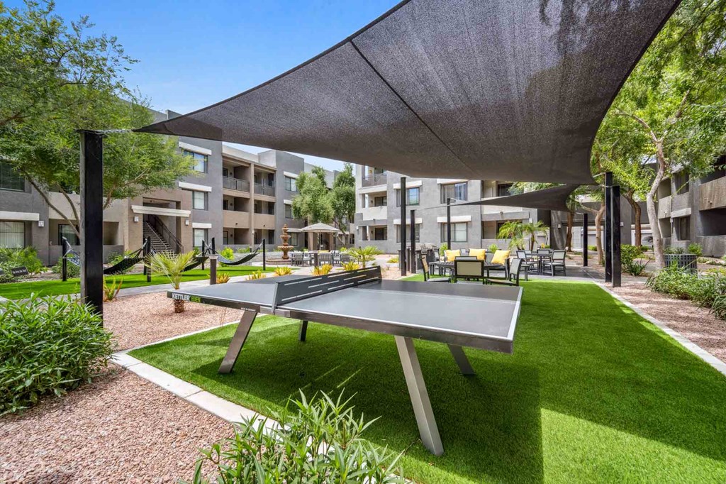 A ping pong table is in the middle of a grassy area.
