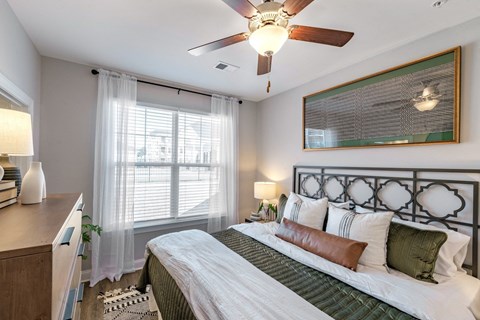 A bedroom with a bed, nightstand, and window with blinds.