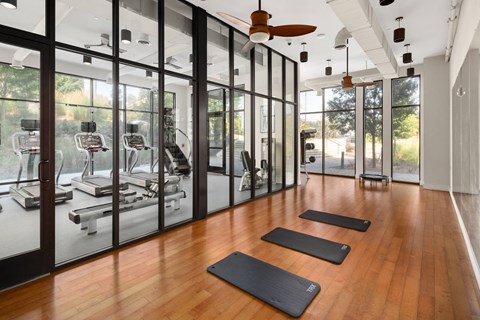 A gym with a row of black mats on the wooden floor.