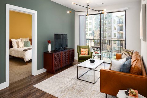 A living room with a brown leather couch, a wooden cabinet, and a white sofa.