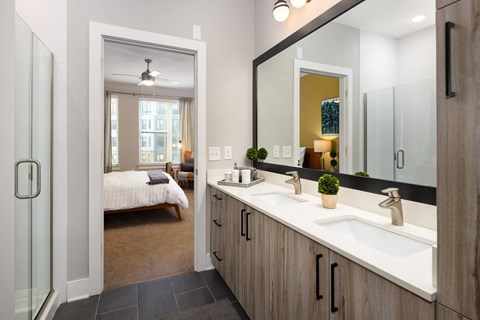 A bathroom with a large mirror, a bed, and a window.