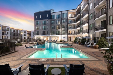 A swimming pool surrounded by chairs and buildings.