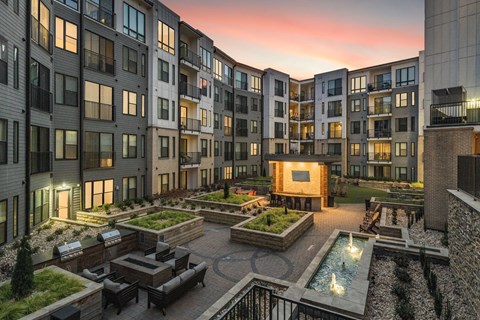 A courtyard surrounded by apartment buildings with a fountain in the middle.
