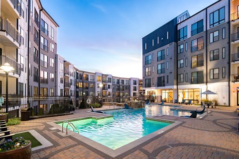 A swimming pool surrounded by apartment buildings at dusk.