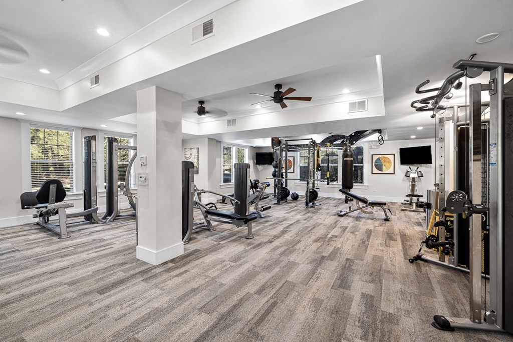 A spacious gym with a variety of equipment and a ceiling fan.