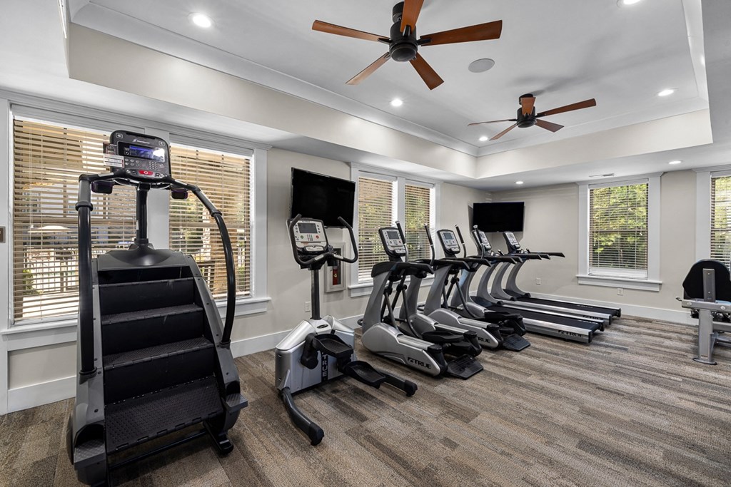 A gym with treadmills, exercise bikes, and a fan.