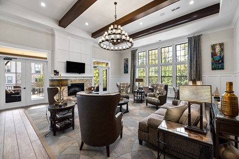 A living room with a brown sofa and a chandelier.