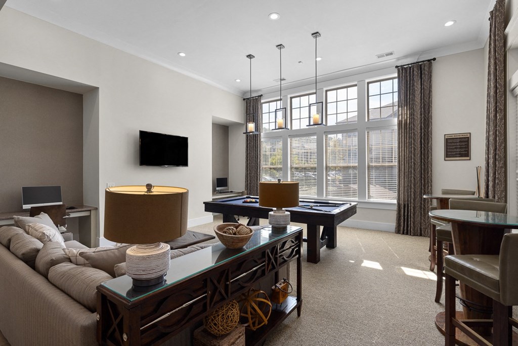 A well-lit living room with a large window and a flat screen TV mounted on the wall.