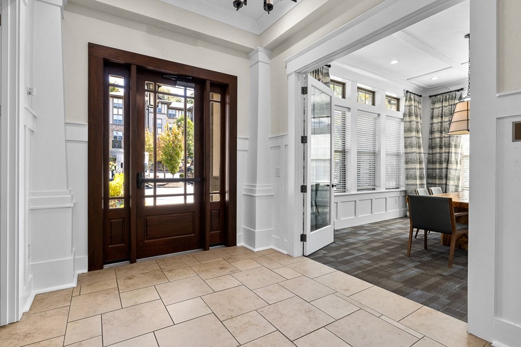 A room with a brown door and a table with a chair.