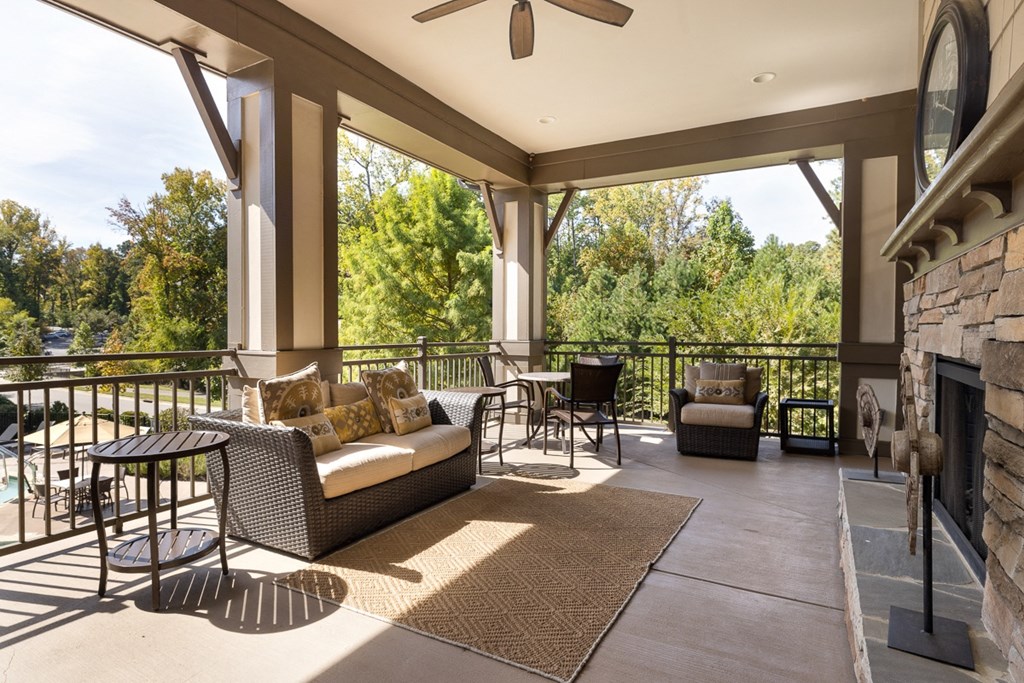 A patio with a couch, chairs, and a table with a fan.