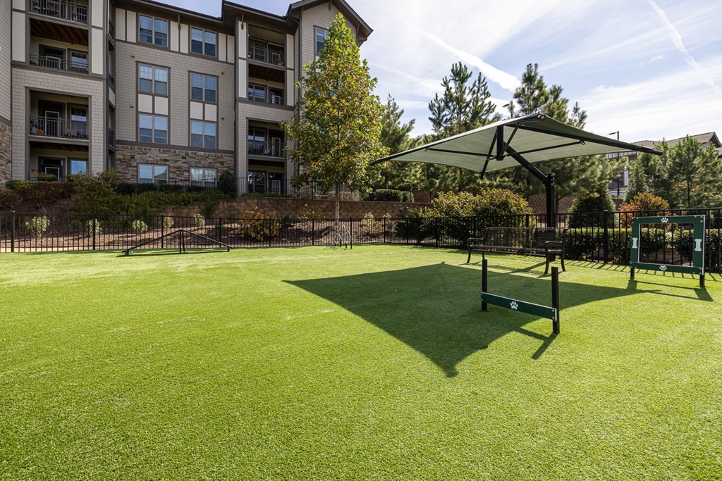 A grassy area with a bench and a canopy in front of a building.