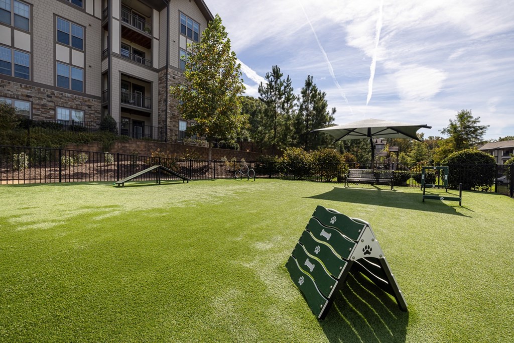 A large green park area with a slide and a building in the background.