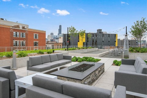 A patio with grey couches and a fire pit.