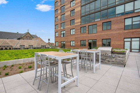 A patio with a table and chairs is in front of a modern building.