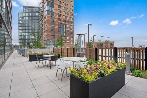 A patio with tables and chairs overlooks a cityscape.