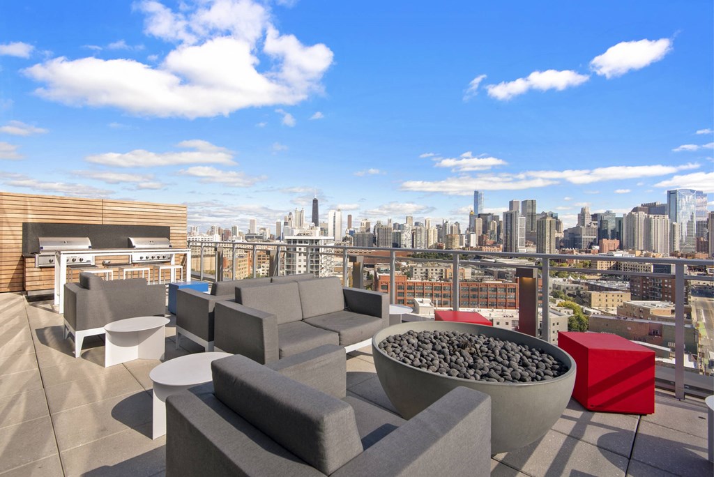 A rooftop patio with grey couches and a bowl of stones.