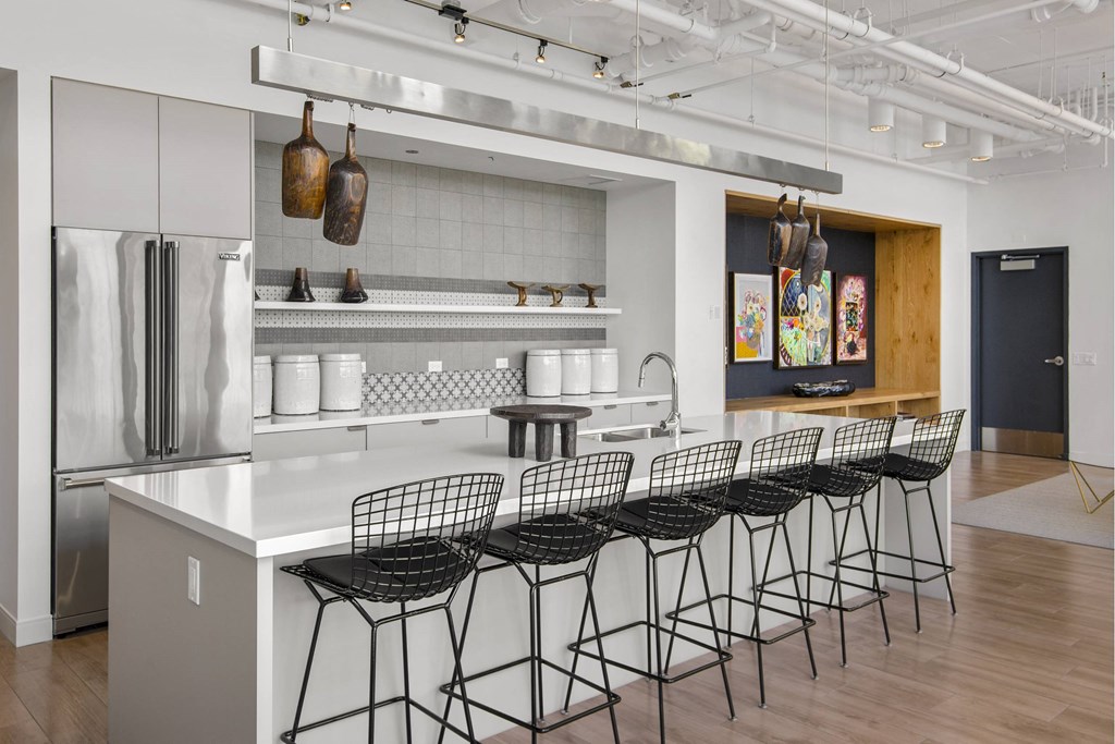 A kitchen with a white counter top and black chairs.