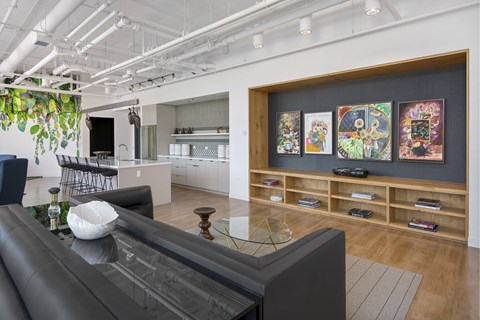 A living room with a black couch and a wall with four paintings.