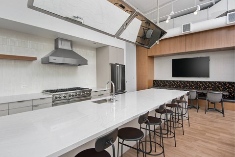 A modern kitchen with a long white counter and bar stools.