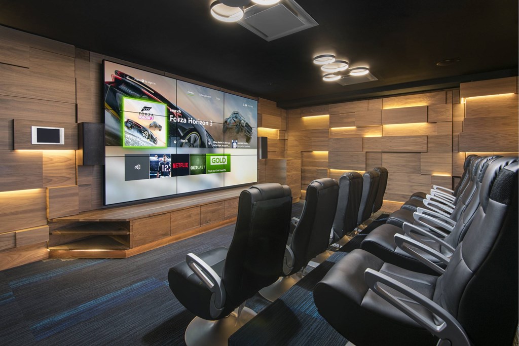 A modern home theater with black leather chairs and a large screen displaying movie options.