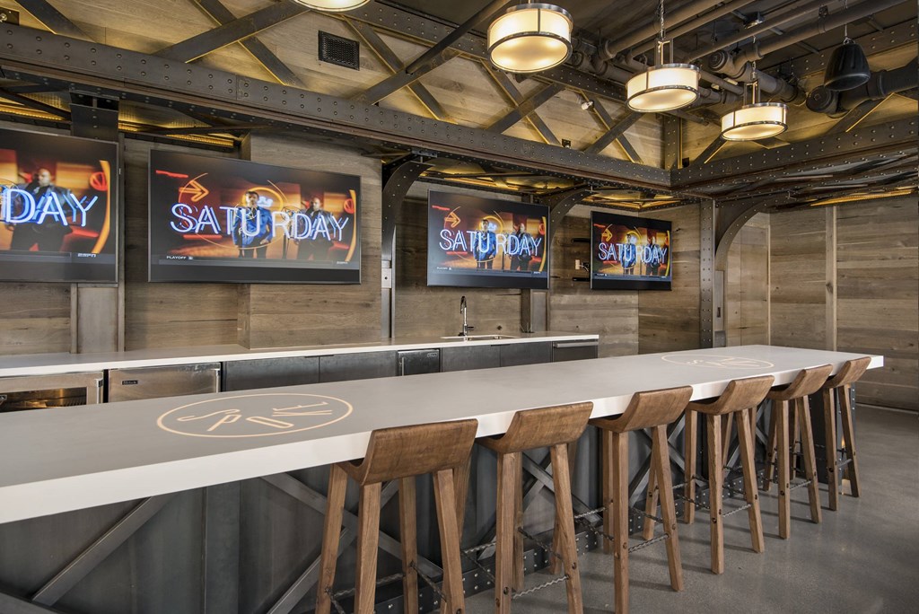 A long white bar with wooden stools and signs that say Saturday.