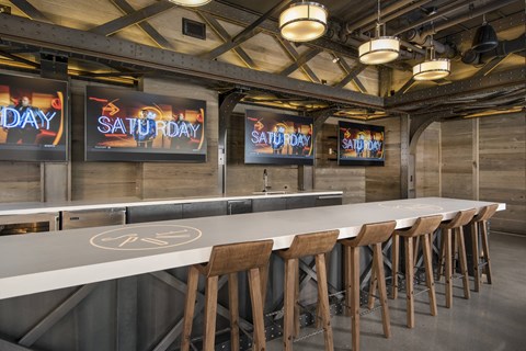 A long white bar with wooden stools and signs that say Saturday.