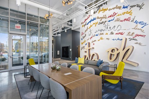 A conference room with a long table and chairs, a TV, and a wall with writing on it.