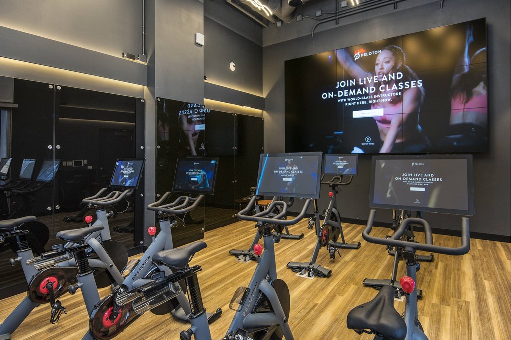 A gym with stationary bikes and a screen displaying "Join live and on-demand classes".
