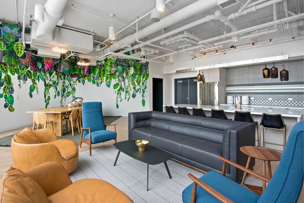 A room with a black couch and a table with a candle on it.