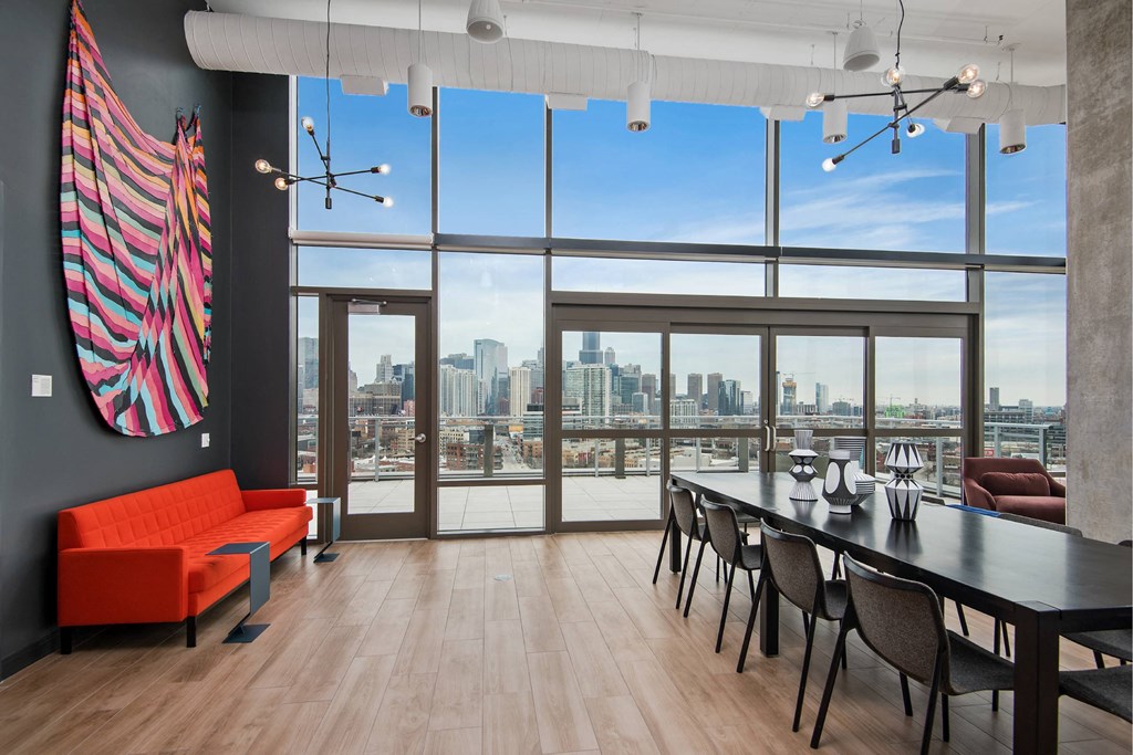 A room with a long table and chairs with a view of the city.