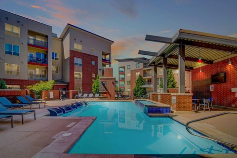 A swimming pool surrounded by lounge chairs and apartment buildings.