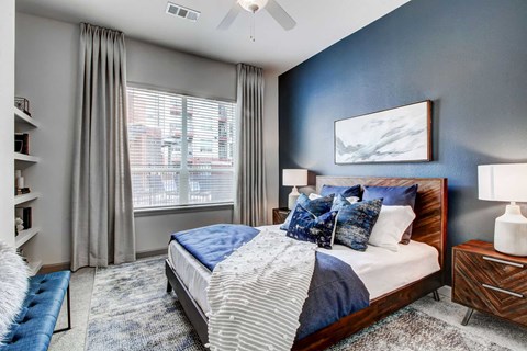 A bedroom with a large bed and a window with curtains.