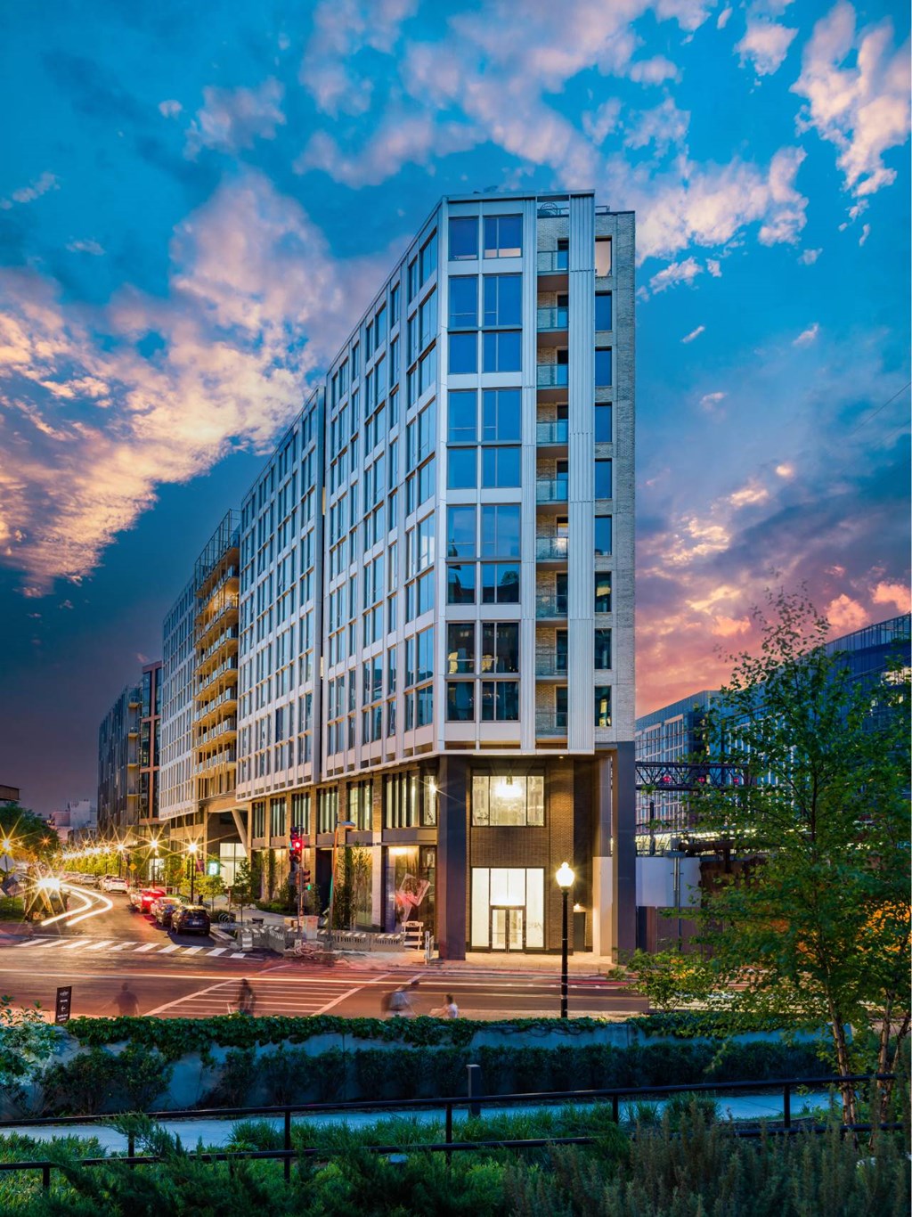 A modern building with a glass facade stands tall against a twilight sky.