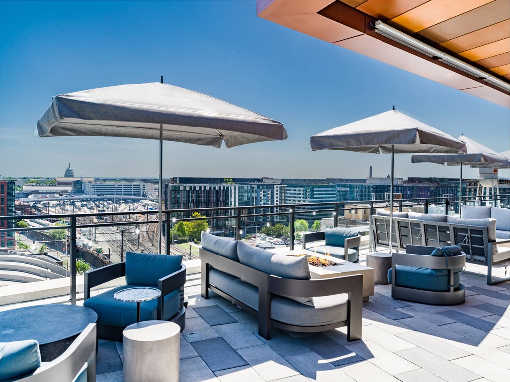 A rooftop patio with white umbrellas and blue cushions.