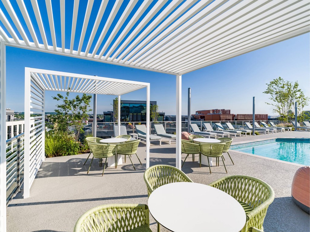 A white patio with green chairs and a table.