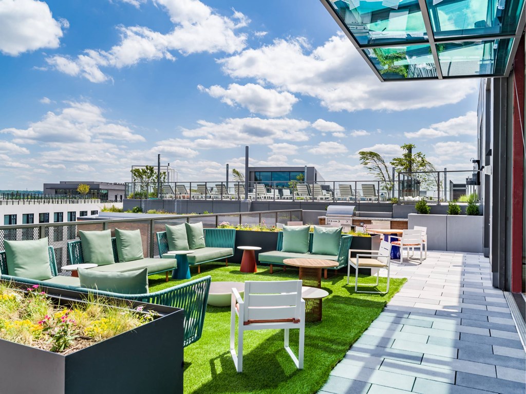 A rooftop patio with green seating and a glass ceiling.