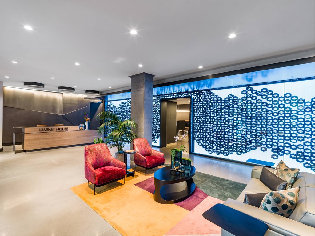 A modern waiting area with red chairs and a wooden floor.