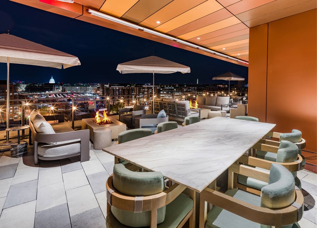 A large table surrounded by chairs is set up on a rooftop terrace.