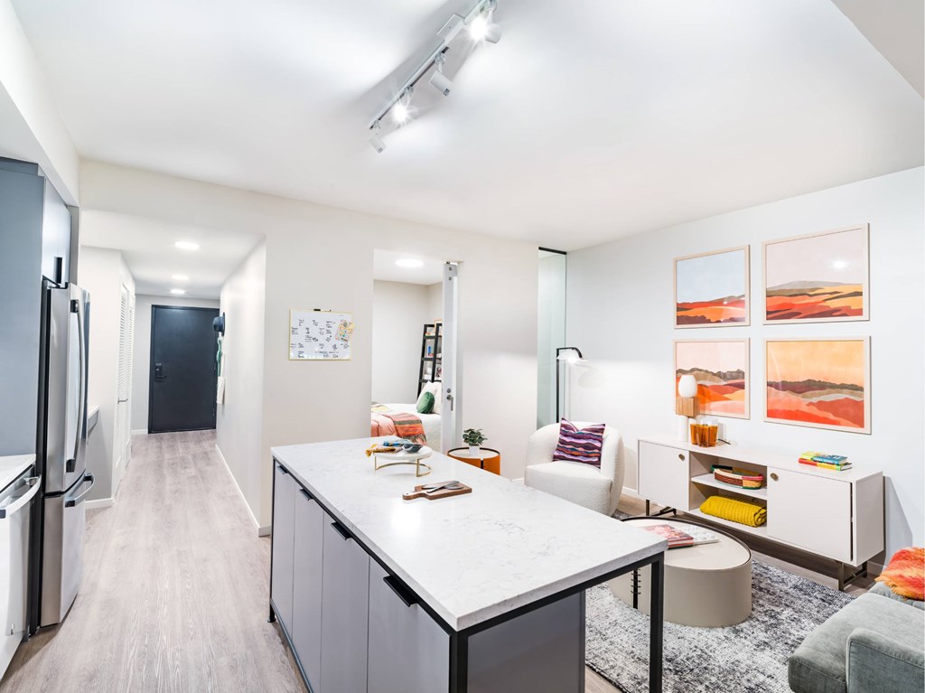 A kitchen with a white countertop and a refrigerator on the left.