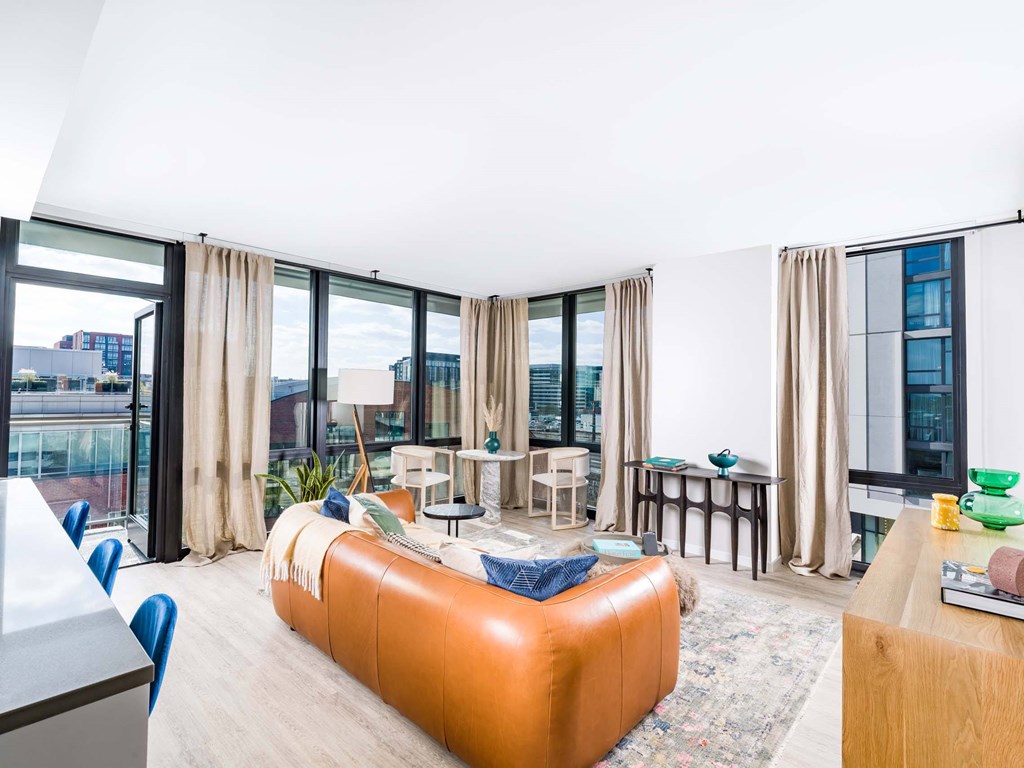 A living room with a large orange sofa and a glass table.