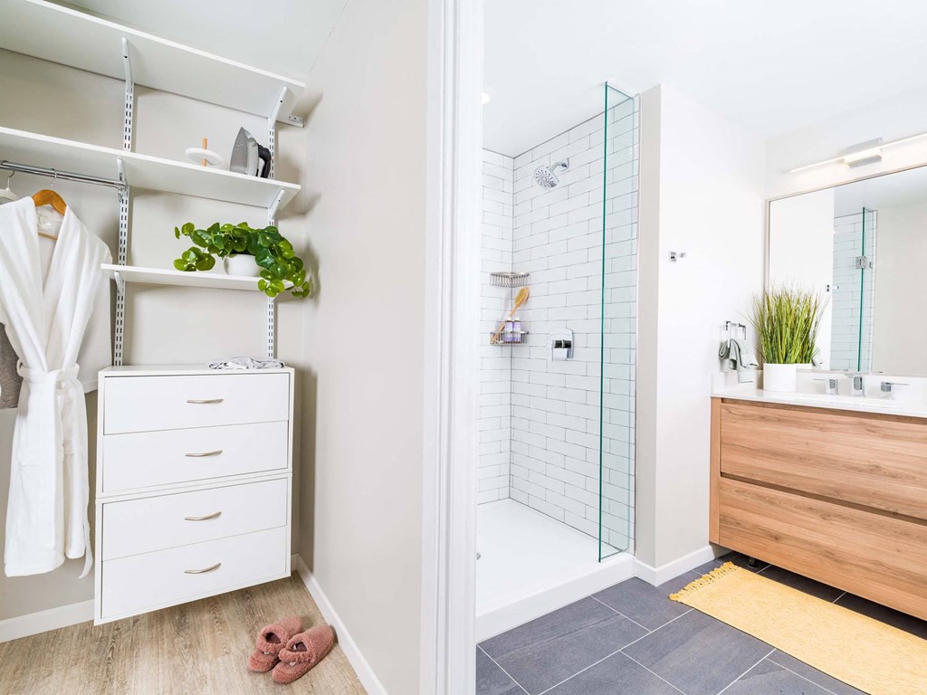 A bathroom with a white towel hanging on a rack and a white robe on a white dresser.