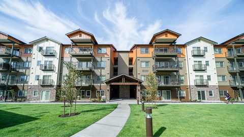 Apartment complex with a green lawn in front and a clear blue sky above.