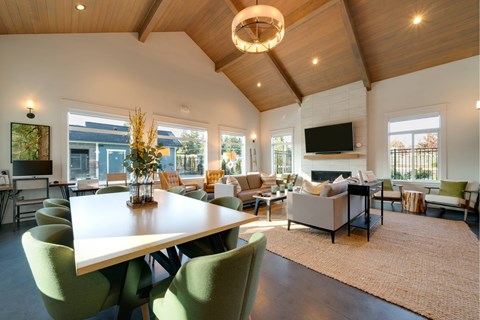 A modern living room with a large white table and green chairs.