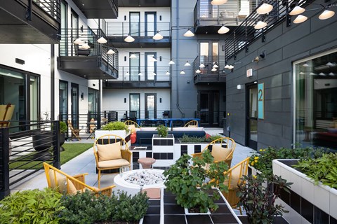 A patio with a fire pit and chairs.