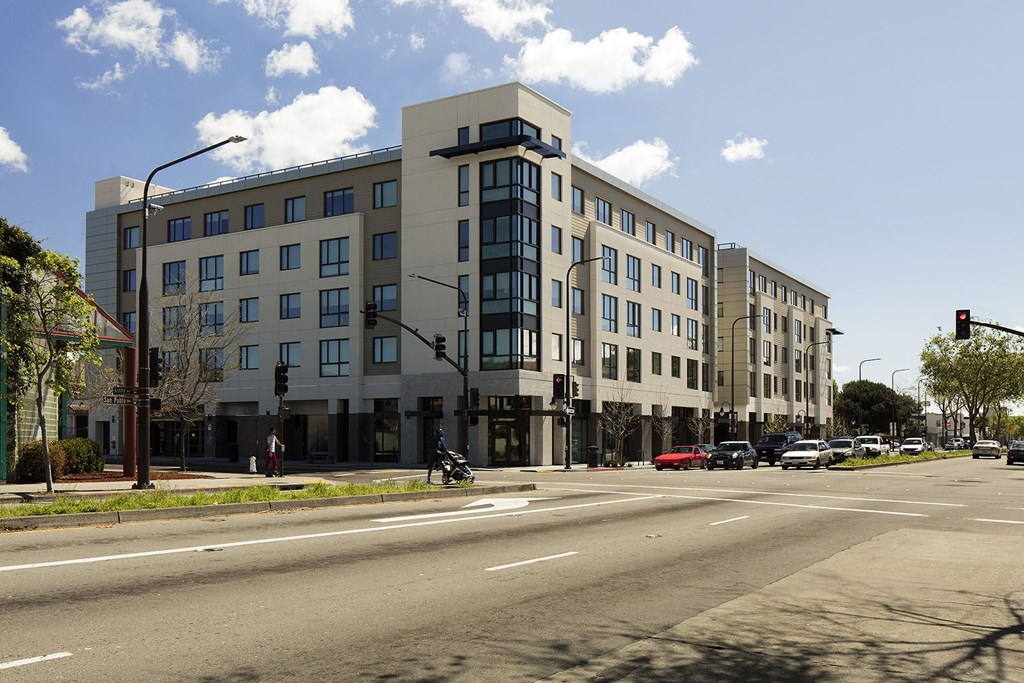 A large building with a grey facade is situated on a street corner.