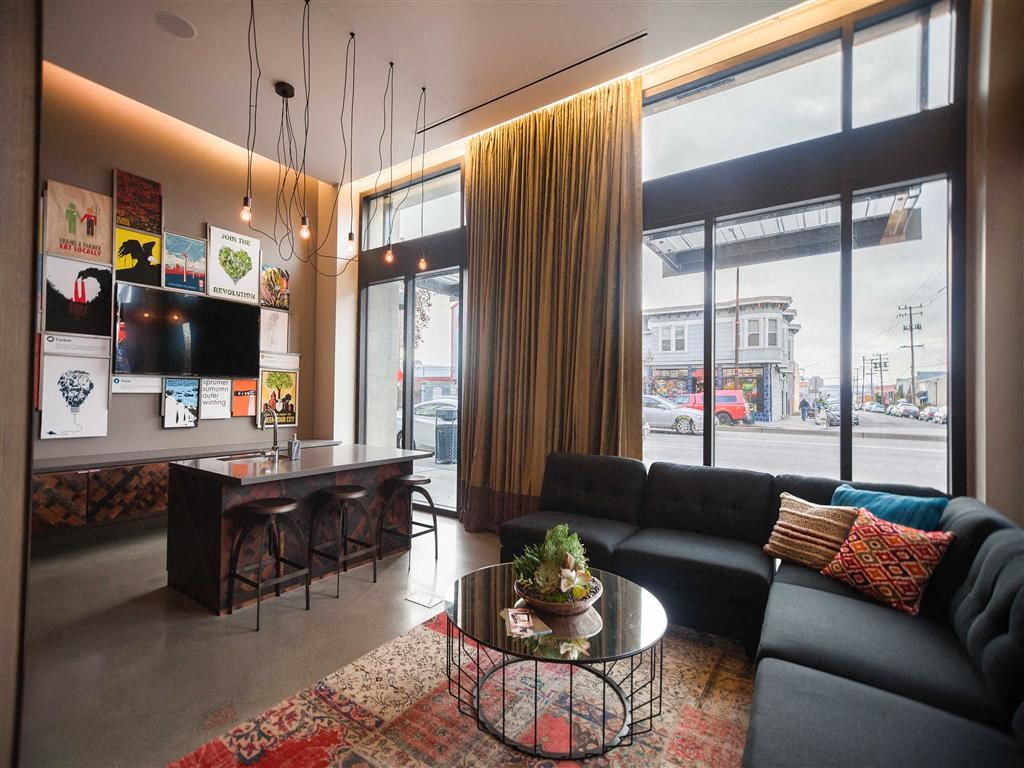 A black couch with a glass table in front of it.