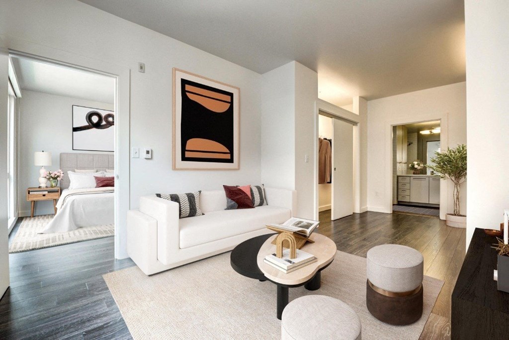 A living room with a white couch and a painting on the wall.