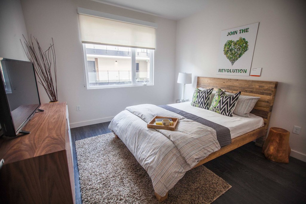 A bedroom with a bed, a television, and a window.