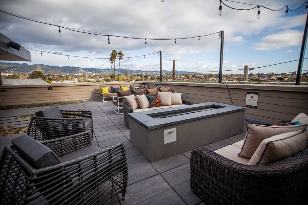 A patio with a hot tub and chairs overlooking a city.